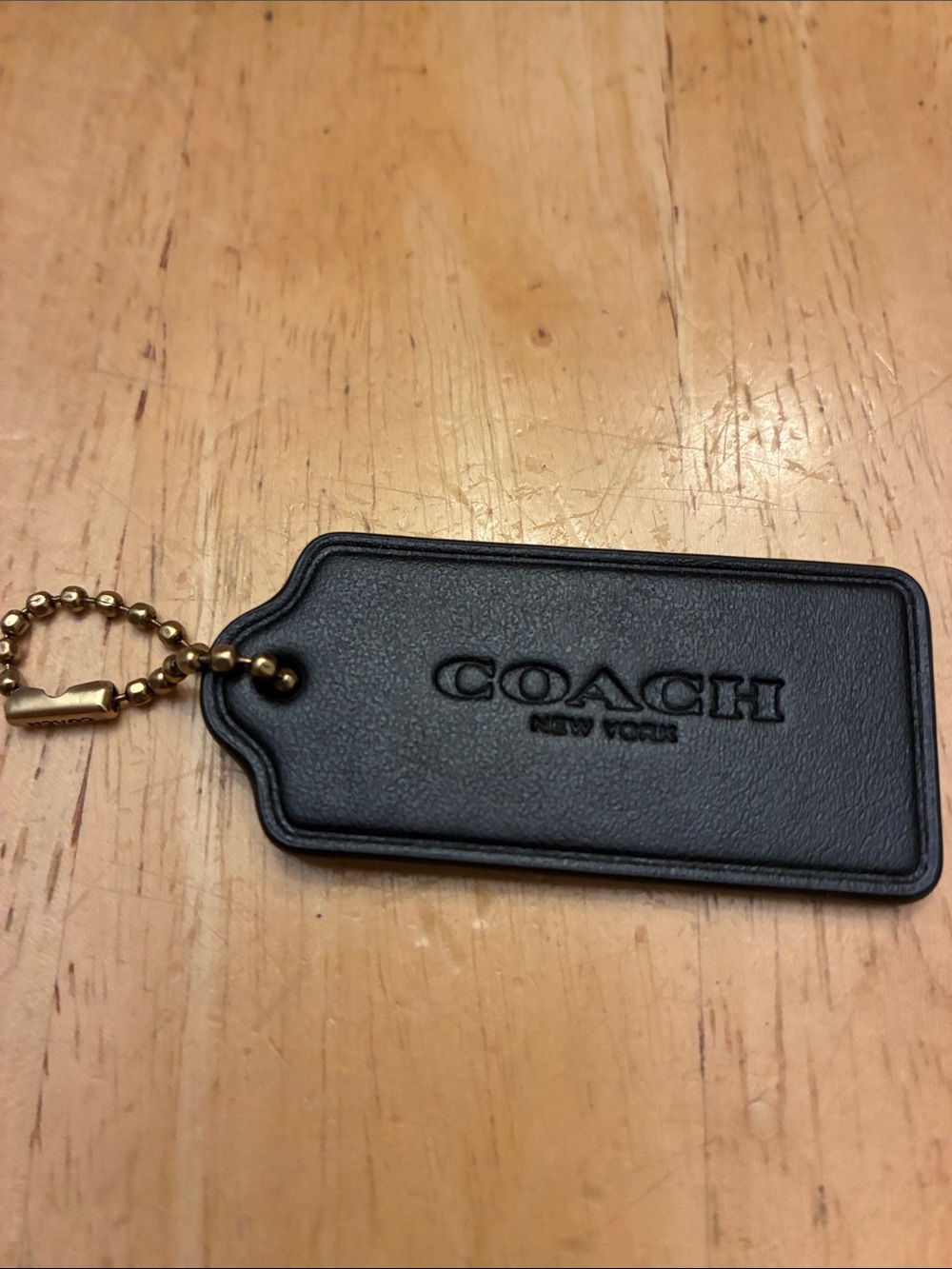 Coach black leather bag tag with brass chain says Coach on chain. New